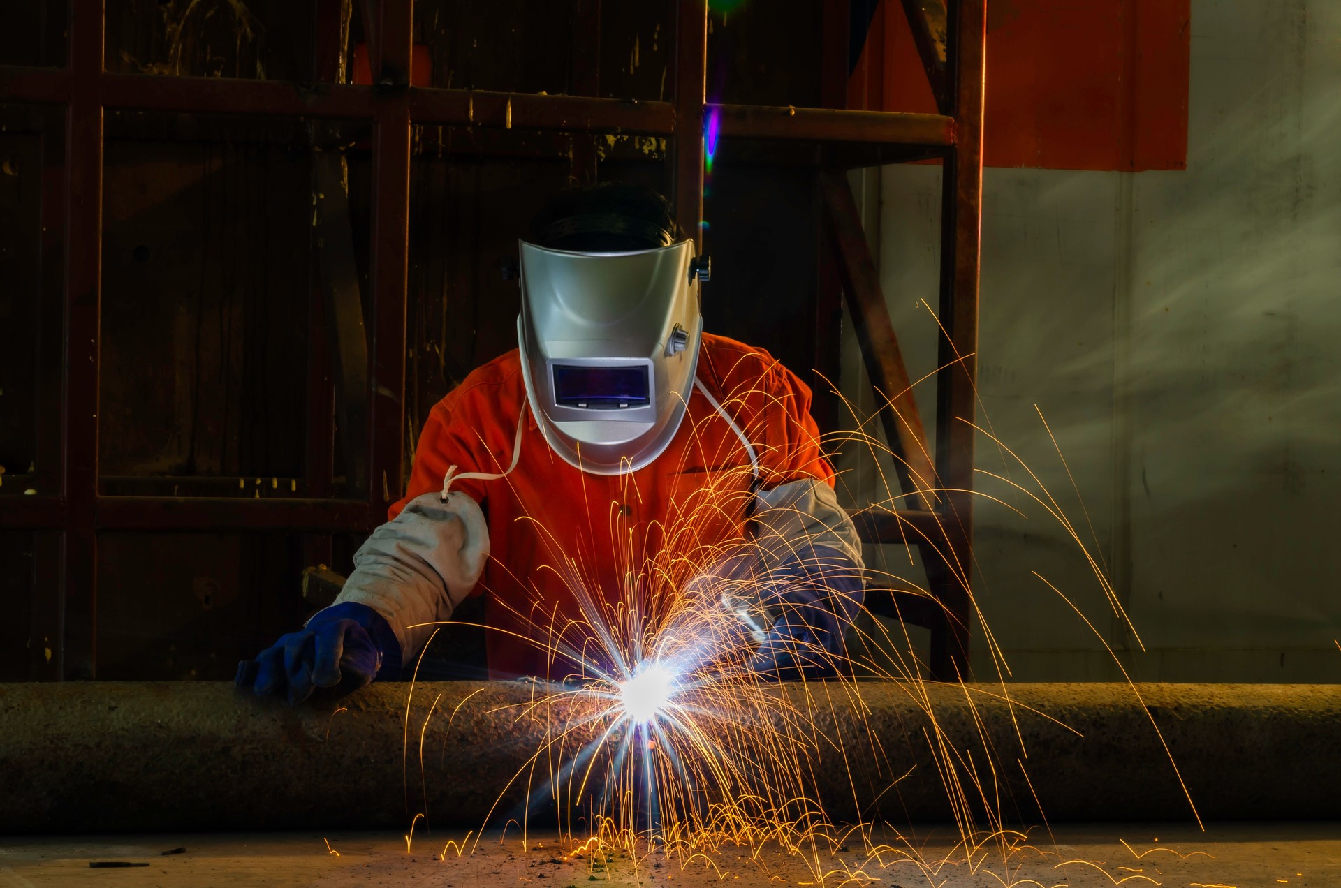 Welder working with electrode at semi automatic arc welding in manufacturing production plant.
